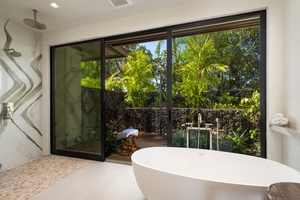 Primary Suite #1: Soak in your private freestanding tub while gazing at tropical gardens through floor-to-ceiling windows.