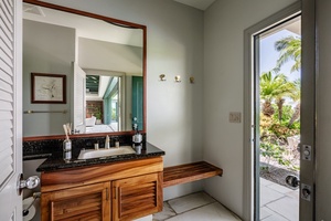 Small bathroom with a wooden vanity and easy outdoor access, perfect for quick freshen-ups.