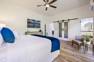 This serene primary bedroom features a king-sized bed and elegant décor, with direct access to the ensuite through stylish barn doors