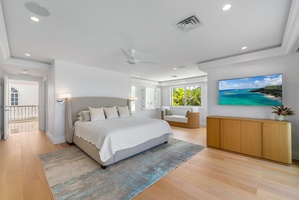 Relax in the bright and airy primary suite, featuring warm wood floors, coastal décor, and beach views.