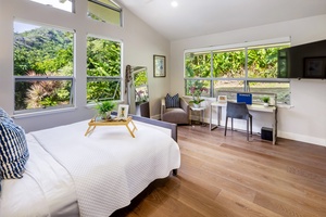 Light-filled bedroom with queen bed, desk, and nature views—perfect for rest and remote work.