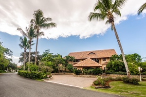 Charming driveway of the estate, surrounded by lush greenery and palm trees.