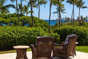Cozy ocean-view seating shaded by palms and vibrant greenery.