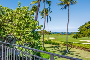 Tropical golf course paradise framed by swaying palms and azure skies, viewed from the lanai.