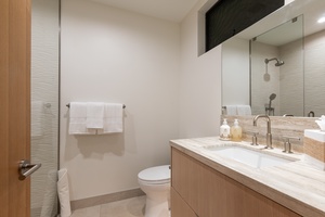 Refresh in your modern bathroom with marble countertops, rainfall shower, and luxury amenities thoughtfully arranged for your comfort.