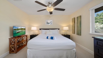 Unwind in the spacious primary suite featuring a plush king bed, ceiling fan, and soft lighting that creates the perfect setting for relaxation.
