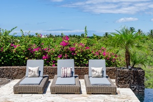 Poolside lounge chairs with vibrant tropical plants in the background, offering a relaxing spot to soak up the sun.