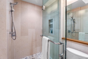 Walk-in shower with rainfall head and clean tile finishes.