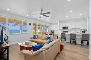 Lower-level living area with coastal textures, ceiling fan, and wall-to-wall ocean views.