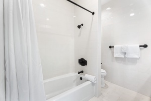 Step into your spotless bathroom featuring a relaxing tub-shower combo with crisp white tiles and fresh towels waiting for you.