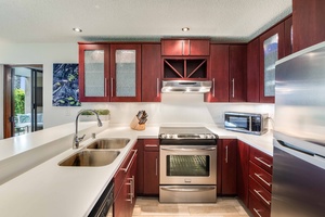 Fully equipped kitchen with sleek cabinetry and stainless steel appliances makes cooking island-style meals a breeze.
