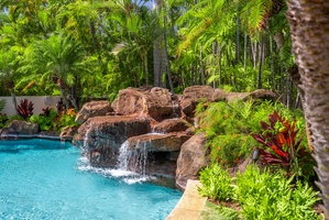 Tropical pool with a natural rock waterfall feature, providing a private oasis for relaxation.