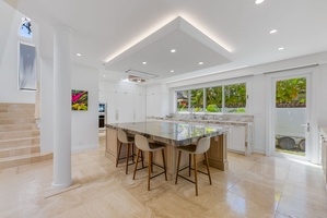 Bright chef’s kitchen with bar seating, ample prep space, and views of the lush backyard.