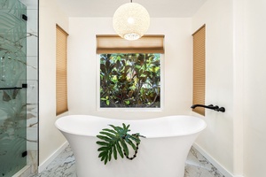 Slip into your luxurious soaking tub beneath the sculptural pendant light, where warm wood blinds frame lush garden views for the ultimate spa retreat.