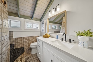Bright and airy bathroom with a modern vanity, vaulted ceilings, and stylish coastal accents.