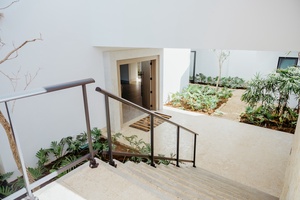 A modern staircase leading to the courtyard area with lush garden beds.