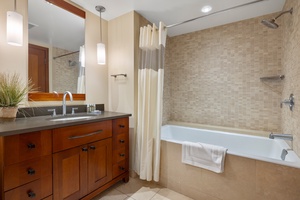 Unwind in your elegant bathroom featuring a deep soaking tub, rainfall shower, and warm wood vanity—perfect for refreshing after your adventures.