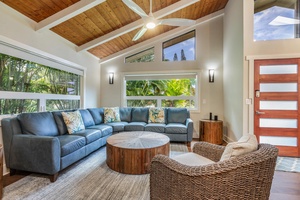 Lounge in the living area with plush sectional sofas, TV, large glass windows and high vaulted ceiling.