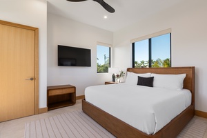 Drift off to sleep in your serene bedroom featuring crisp linens, warm wood accents, and tropical views through expansive windows.