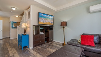 Unwind in your stylish living space with plush leather seating, vibrant coastal decor, and entertainment center for cozy evenings at home.