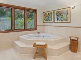 Unwind in your private spa-like sanctuary with a luxurious corner jetted tub and tropical garden views through beautiful wood-framed windows.
