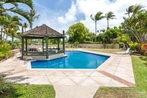 Community pool surrounded by palms and open lawn.