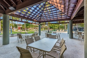 Gather with friends and family under the shaded pavilion, featuring a grilling station and tropical garden surroundings.