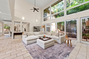 Relax in your spacious living room featuring soaring ceilings, floor-to-ceiling windows, and lush garden views that flood the space with natural light.