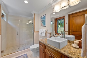 Granite finishes, a glass shower, and thoughtful details bring a spa-like feel to the bathroom.