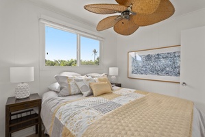 Sleep peacefully in this bright bedroom with tropical ceiling fan and garden views through large windows.