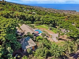 Spectacular aerial view showcasing the property nestled among lush tropical vegetation with ocean views stretching to the horizon.