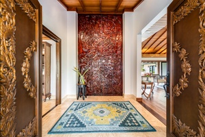 Ornate entryway sets the tone with custom-carved wood doors and natural stone feature wall.