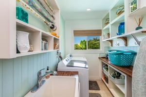 A full laundry room with washer, dryer, utility sink, and storage shelves adds convenience for extended island stays.