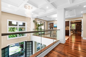 Upper-level landing with glass railing and chandelier lighting.