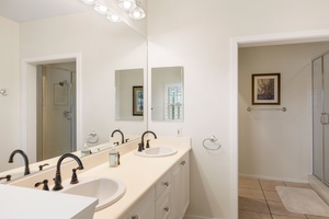 Your spacious ensuite bathroom features dual vanities with elegant bronze fixtures, perfect for getting ready together in comfort and style.