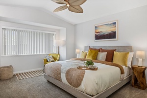 Drift off in the sun-kissed primary suite with king bed, ceiling fan, and tranquil garden views.