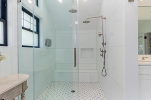 Glass-enclosed walk-in shower with dual rain heads and spa-style elegance.