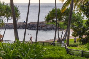 Tranquil beachfront setting framed by swaying palms, with a sheltered lagoon and ocean beyond—a picturesque tropical escape awaits near the property.