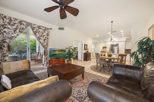 Settle into your spacious living room where rich leather seating and tropical plants create a warm, inviting atmosphere for relaxing evenings.