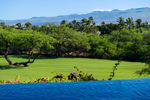 Infinity pool with vibrant greenery and mountain views in the background.