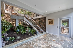 Stone patio and garden-level access offering privacy and tropical charm.
