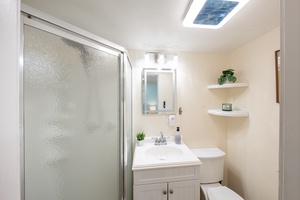 Bright light over the glass shower and vanity, clean and simple.