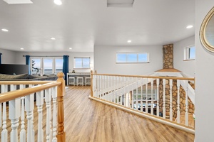 Your upstairs loft offers bright, airy space with wood railings and ocean glimpses through multiple windows.