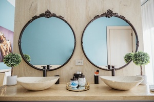 Elegant primary bathroom with a double vanity, decorative mirrors, and stylish vessel sinks.