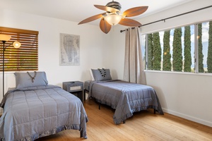 This flexible guest bedroom with two twin beds is perfect for kids, teens, or a shared space—complete with ceiling fan and garden views.