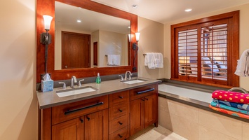 Luxurious guest bath with a soaking tub, dual vanity, and wood accents.
