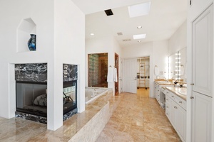 Primary bathroom has double sided glass fireplace, jetted tub, shower, double sinks and massive walk in closet.