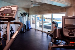 Exercise with ocean views in the bright and airy home fitness center.