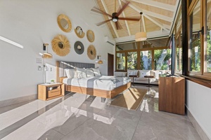 The primary bedroom features a large windows offering a view of the lush greenery outside.