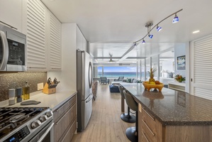 The stunning kitchen flows seamlessly to the living area, where granite counters and modern appliances await your culinary adventures with breathtaking sea views.